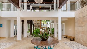 A spacious indoor area with a central wooden table, a potted plant, and a bench. - Luxury villa at Puntacana Resort & Club (Punta Cana)
