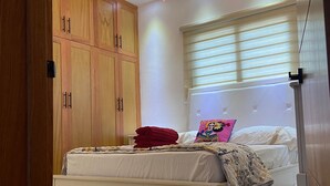 A bedroom with a large bed, wooden wardrobe, and a chandelier. - Verdana Villa. (San Francisco de Macorís)