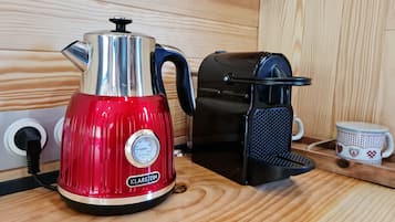 Eine rote Kaffeemaschine mit Temperaturanzeige und eine schwarze Espressomaschine auf einer Holzauskład.