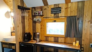 A rustic kitchen with wooden walls, a sink, a coffee maker, and two stools. - Cab'ânes du Pibeste (Segus)
