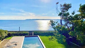 En swimmingpool med udsigt til havet og fjerne bakker.