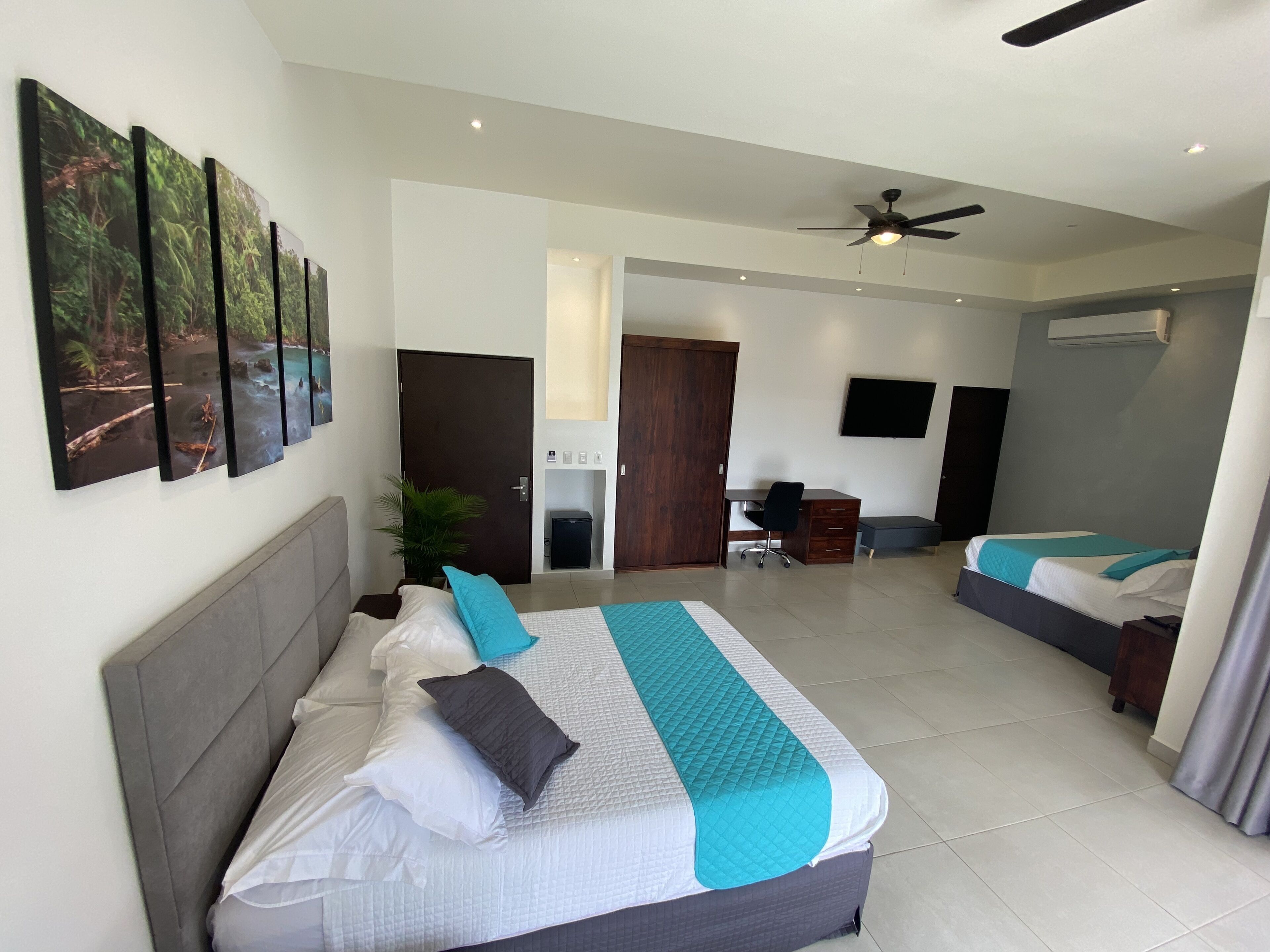 A hotel room with a large bed, a desk, a chair, and a TV.