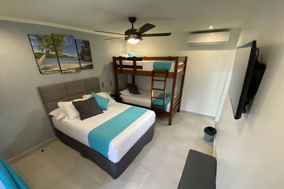Un dormitorio con literas, un televisor de pantalla plana y un ventilador de techo.