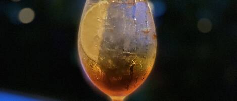 A glass of amber-colored drink on a wooden table with a blurred background.