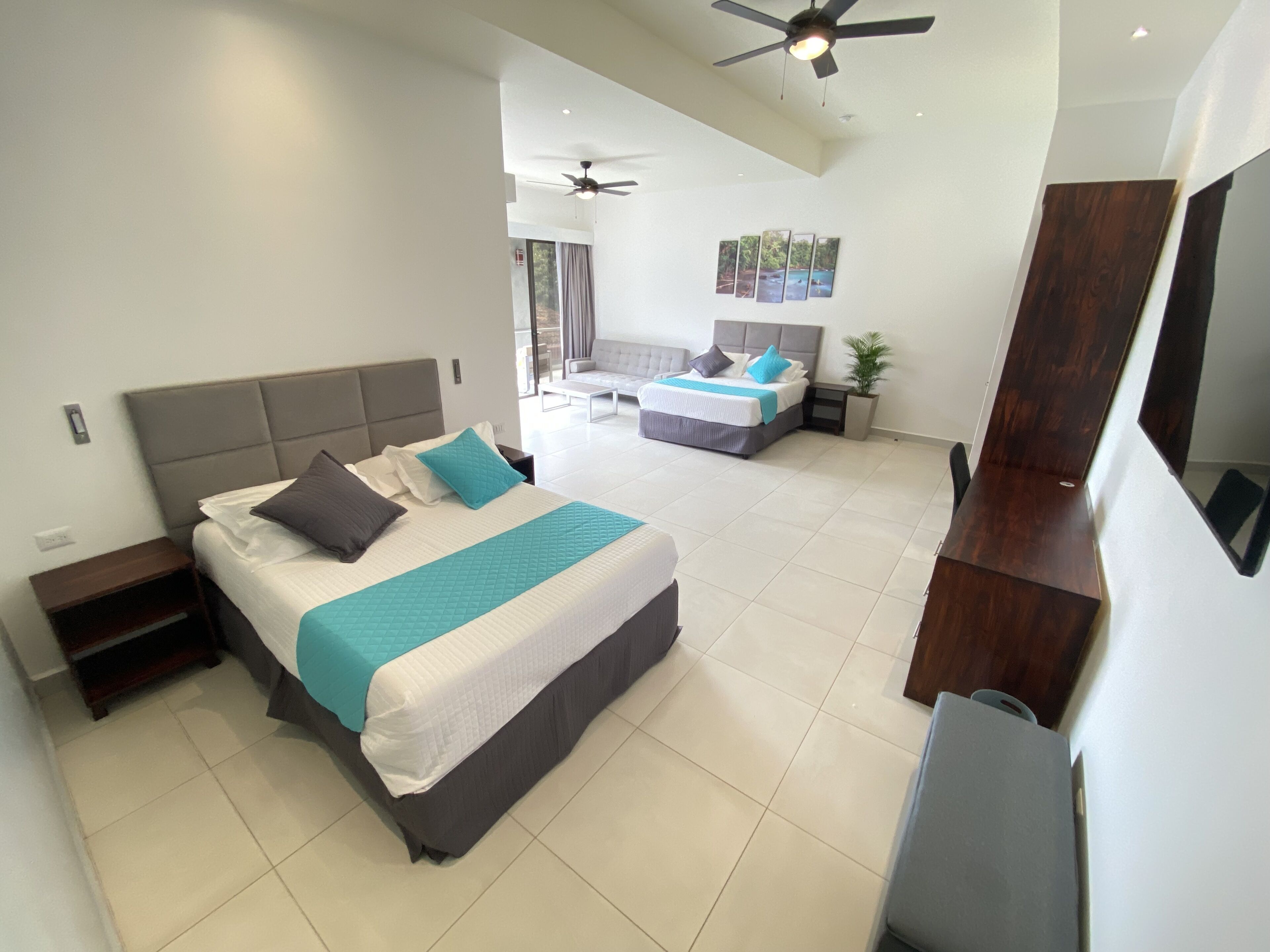 A modern hotel room with two beds, a ceiling fan, a large mirror, and a view of the outdoors.