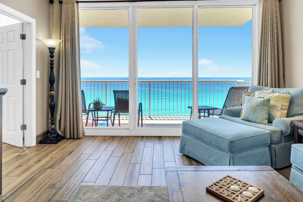 A room with a view of the ocean, a sofa, a lamp, and a table with a tray.
