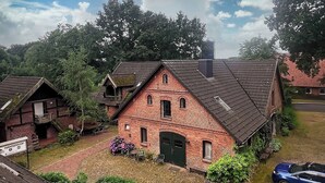 Une maison traditionnelle en briques, dotée d’un toit à forte pente, d’un porche à l’avant et d’un petit jardin.