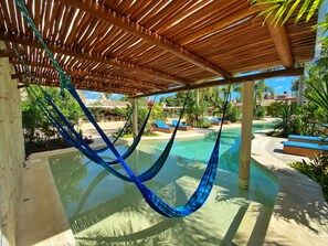 A hammock under a wooden pergola over a swimming pool with lounge chairs and tropical plants. - Blue Palm Bacalar (Bacalar)