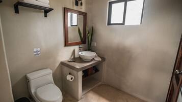 A bathroom with a toilet, sink, and a window.