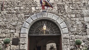 An arched entrance with a lantern, stone walls, and flags.
