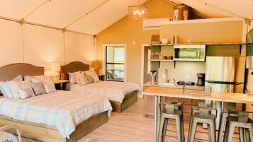 A cozy tent-style accommodation with two beds, a kitchenette, and a dining area.