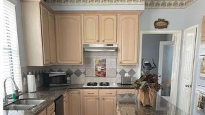 Una cocina con armarios de madera, encimera de granito y una isla central.