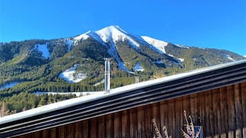 Une montagne aux sommets enneigés, une structure en bois au premier plan et un ciel bleu dégagé.