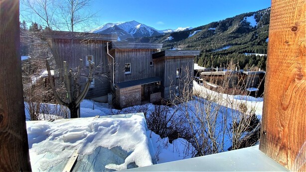 A wooden cabin with a view of a snow-covered mountain.