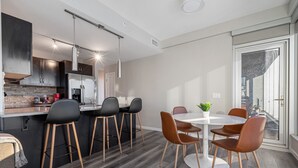 Une cuisine moderne avec des meubles de couleur sombre, un réfrigérateur en acier inoxydable et un coin bar équipé de tabourets.