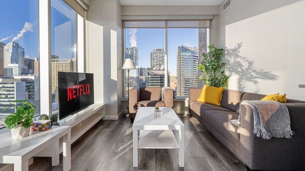 Un salon moderne avec une grande télévision, un canapé, une table basse et une vue sur la ville.
