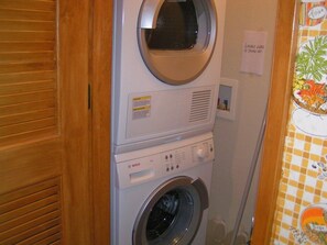 A stacked washer and dryer unit with a control panel and a small shelf with items. - Courchevel 26 in Mammoth Lakes, CA (Mammoth Lakes)