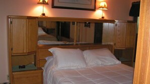 Een slaapkamer met een bed, nachtkastjes, een spiegel en twee wandlampen.