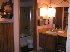 A bathroom with a shower, toilet, sink, and mirror.