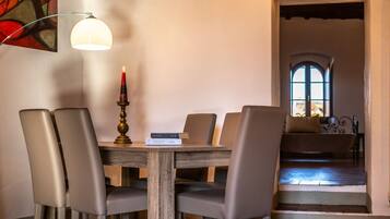 Un comedor con una mesa de madera, cuatro sillas, una vela y un libro titulado 'STEVE JOBS'.