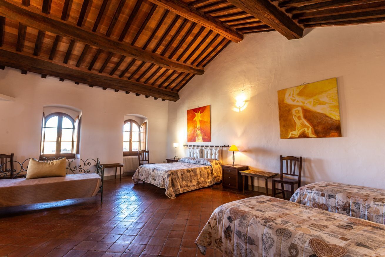 Una habitación acogedora con dos camas, techo de madera y un cuadro grande en la pared.