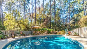 A swimming pool surrounded by trees and a wooden deck with chairs. - RESTFUL RETREAT! (Hilton Head Island)