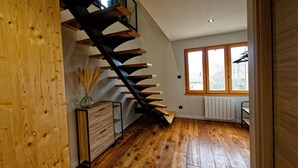 A modern interior with a wooden staircase, a radiator, and a window with a view.