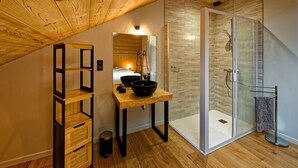 A modern bathroom with a wooden vanity, a glass shower enclosure, and a wooden ceiling.