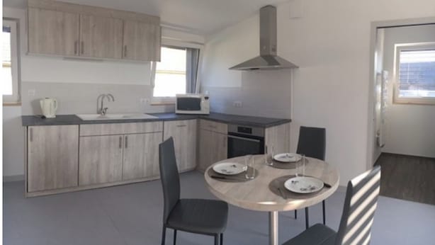 Eine moderne Küche mit Holzausstattung, einer Mikrowelle und einem Essbereich mit Tisch und Stühlen.