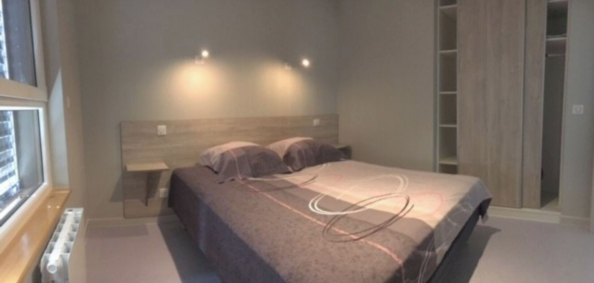 A bedroom with a bed, bedside tables, and a wardrobe.