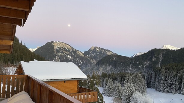 Una cabana de fusta amb un balcó que fa vedes a un paisatge de muntanya cobert de neu.
