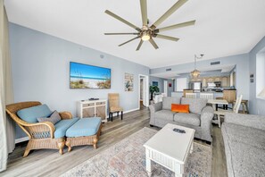 A living room with a ceiling fan, a television, and a dining area with a table and chairs. - Majestic Sun 1201A - Top Floor! Updated Corner Unit, Incredible Views! (Saint Cyr)