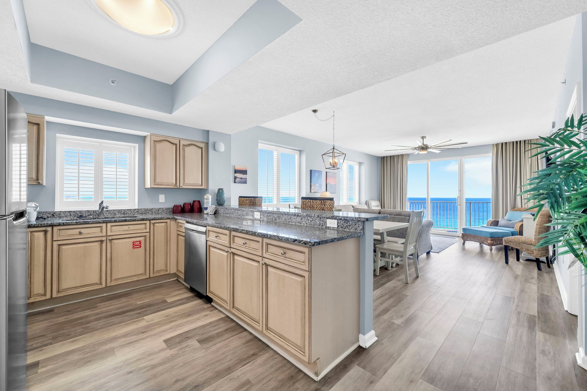 A spacious kitchen with a central island, wooden cabinets, and a view to the living area.