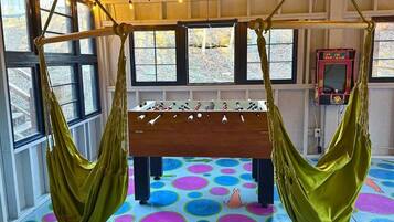 Une table de baby-foot dans une pièce dotée de grandes fenêtres et de carreaux de sol aux couleurs vives.