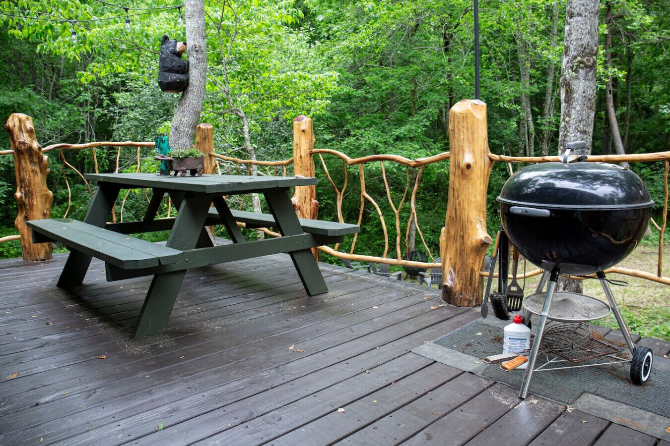Una terraza de madera con una mesa de picnic y una parrilla portátil.
