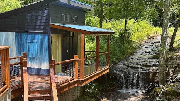 Um deck de madeira com guarda-corpo de metal dando vista para uma cachoeira.