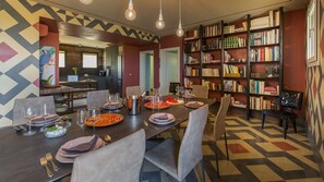 Ein Essbereich mit einem langen Tisch, gedeckt für sechs Personen, umgeben von Bücherregalen voller Bücher.
