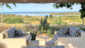 An outdoor seating area with two sofas facing a scenic view of the sea and landscape. - Villa Majoli 9, Emma Villas (Noto)