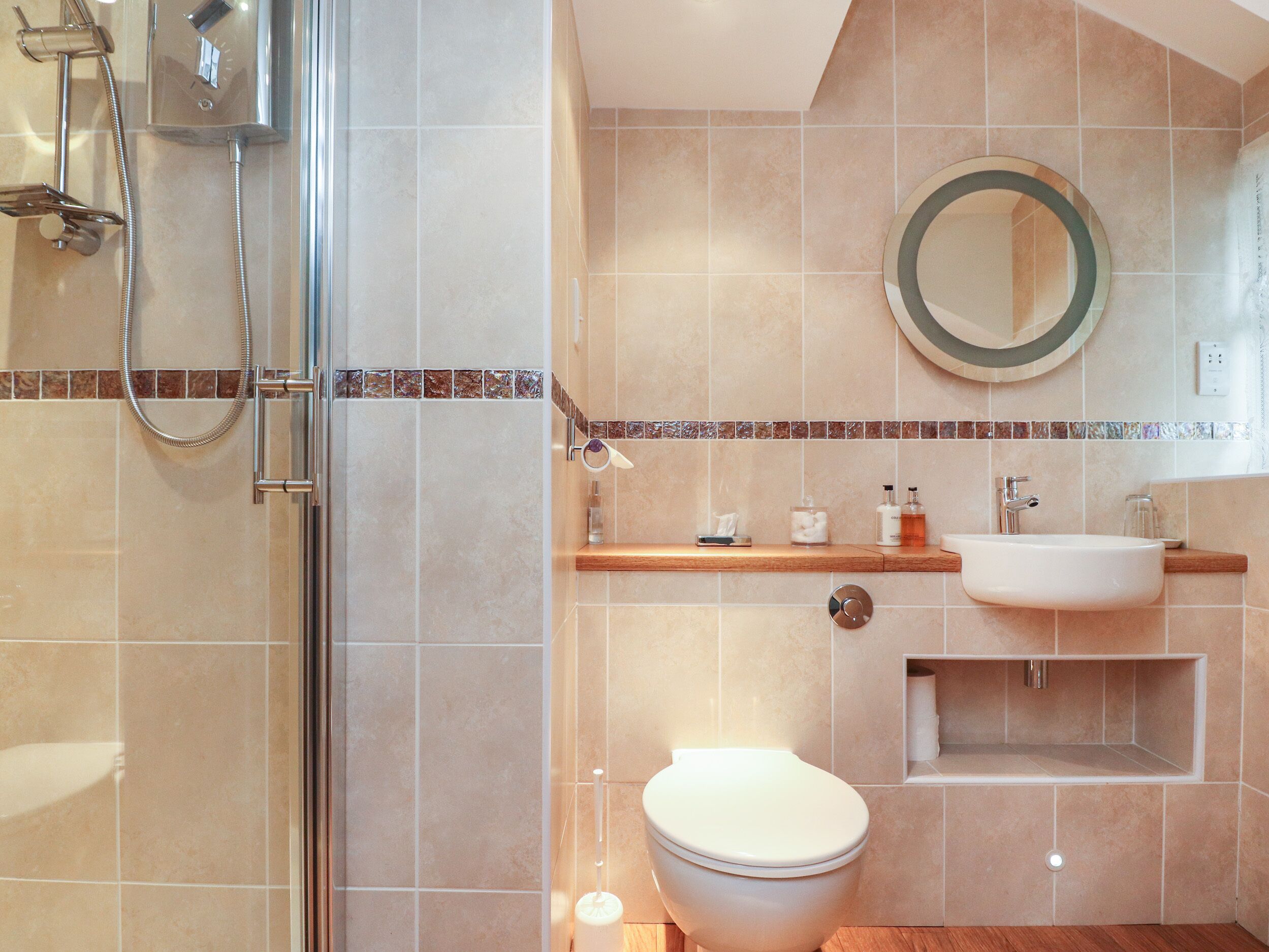 A bathroom with a glass shower enclosure, a toilet, a sink, and a mirror.