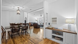 A spacious living area with a dining table and chairs, a sofa, and a kitchen area with a counter and cabinets.