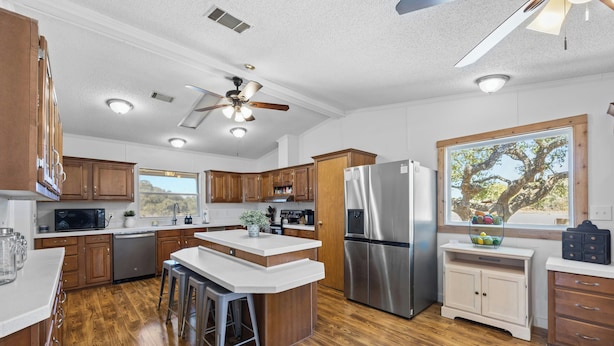 A modern kitchen with wooden cabinets, stainless steel appliances, and a central island with stools.