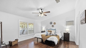 A bedroom with a bed, a ceiling fan, a window, and a nightstand.
