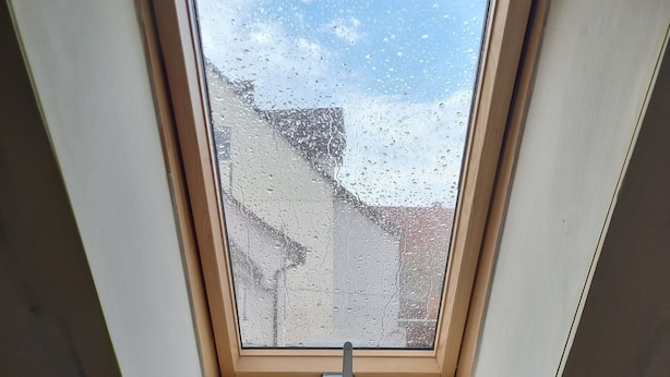 Een dakraam met houten frame en metalen vergrendeling.