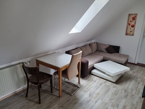 A loft-style room with a dining table, chairs, a sofa, and a white coffee table.