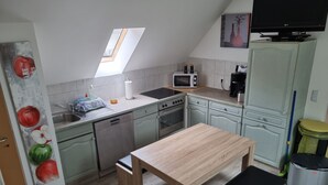 Een kleine keuken met dakraam, een magnetron, een koffiezetapparaat en een eethoek met een bank.