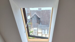 Een kamer met een schuine kap en dakraam, een radiator, en een effen muur.