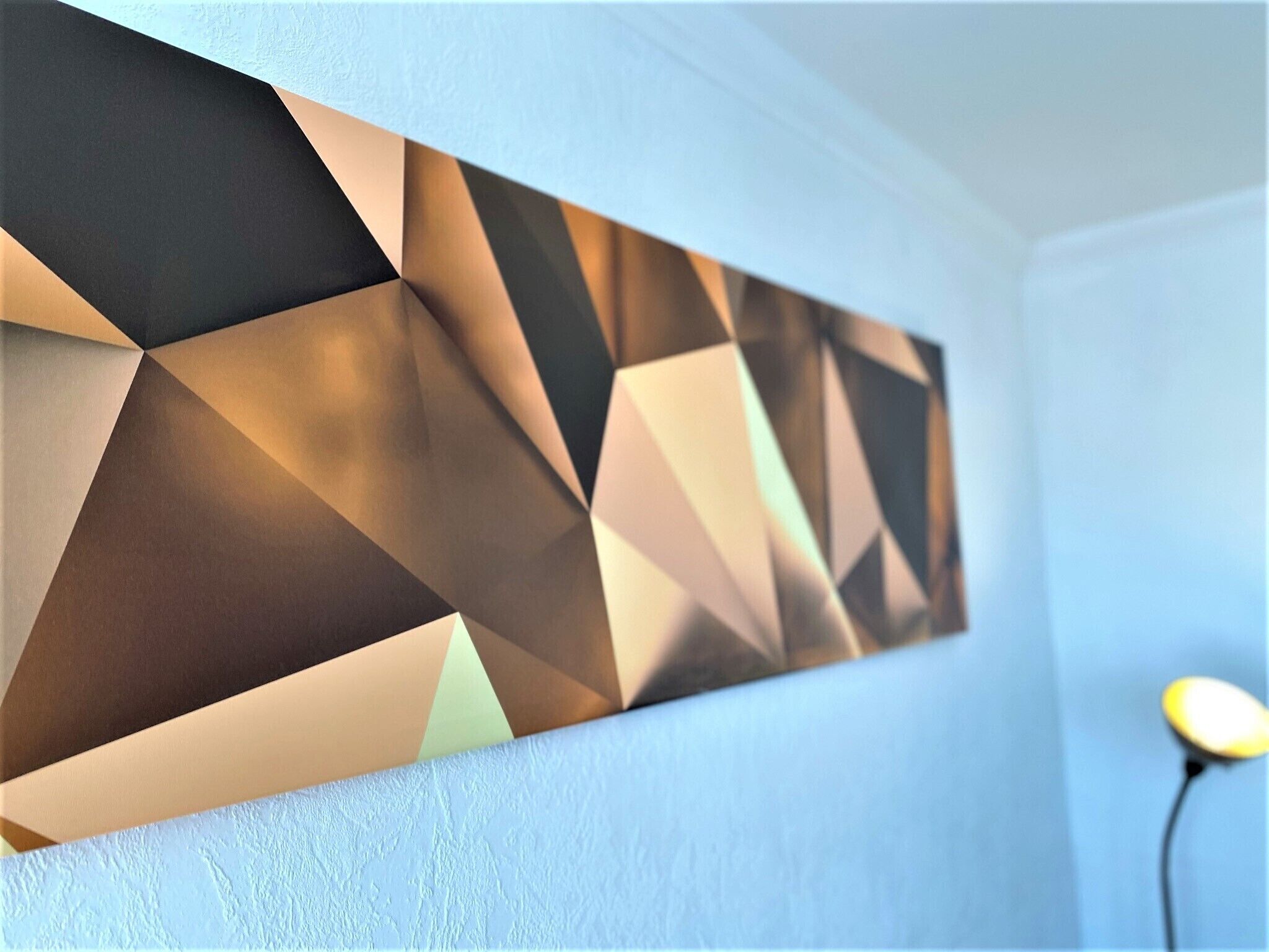 Une œuvre d’art murale aux motifs géométriques, avec une source de lumière placée derrière, créant ainsi un effet d’ombre.