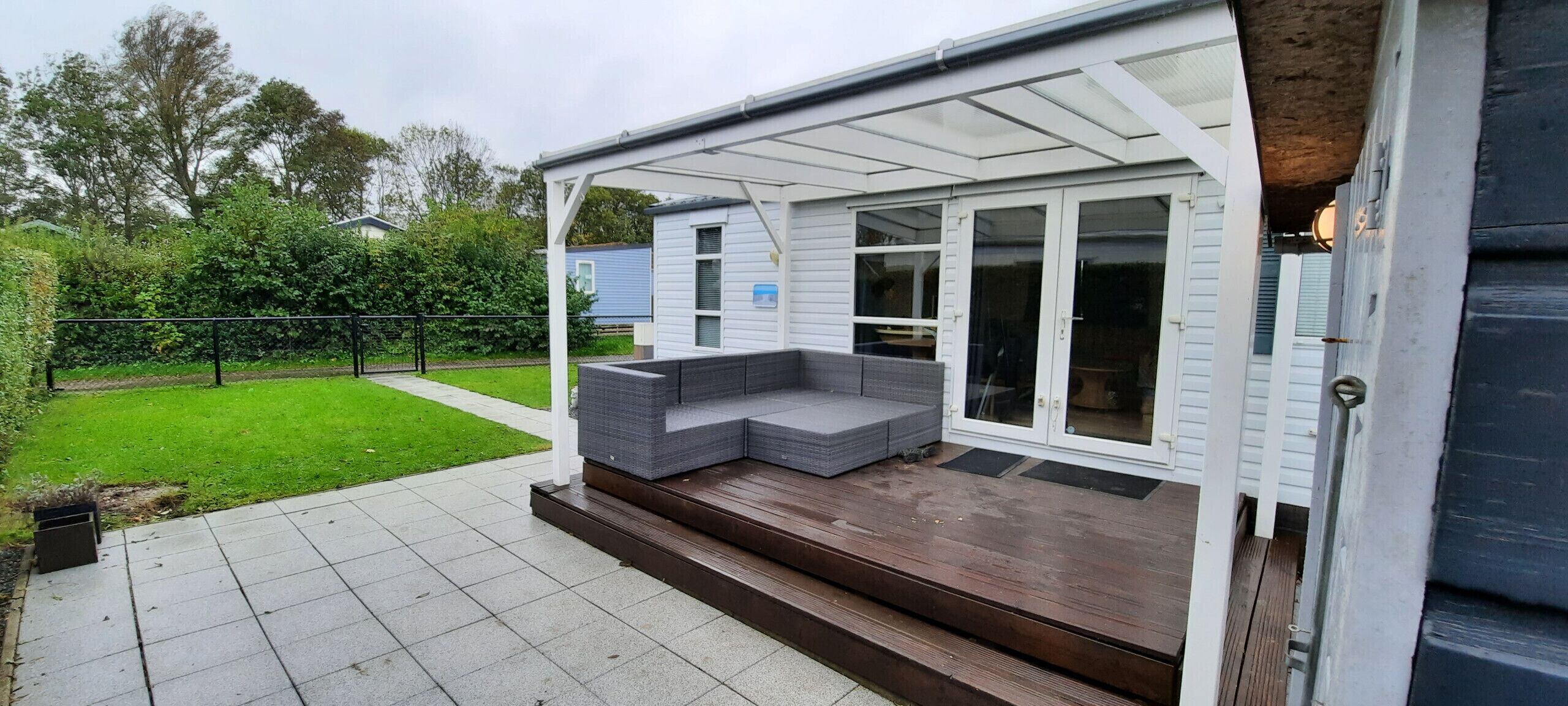 Un espace extérieur abrité avec une terrasse en bois et un banc intégré.