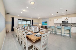 Una cocina moderna con armarios blancos, un microondas y un comedor con mesa de madera y sillas blancas.