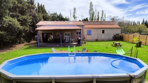 An above-ground swimming pool with a patio area, a wooden deck, and a house in the background. - House garden swimming pool play in the country (Camélas)